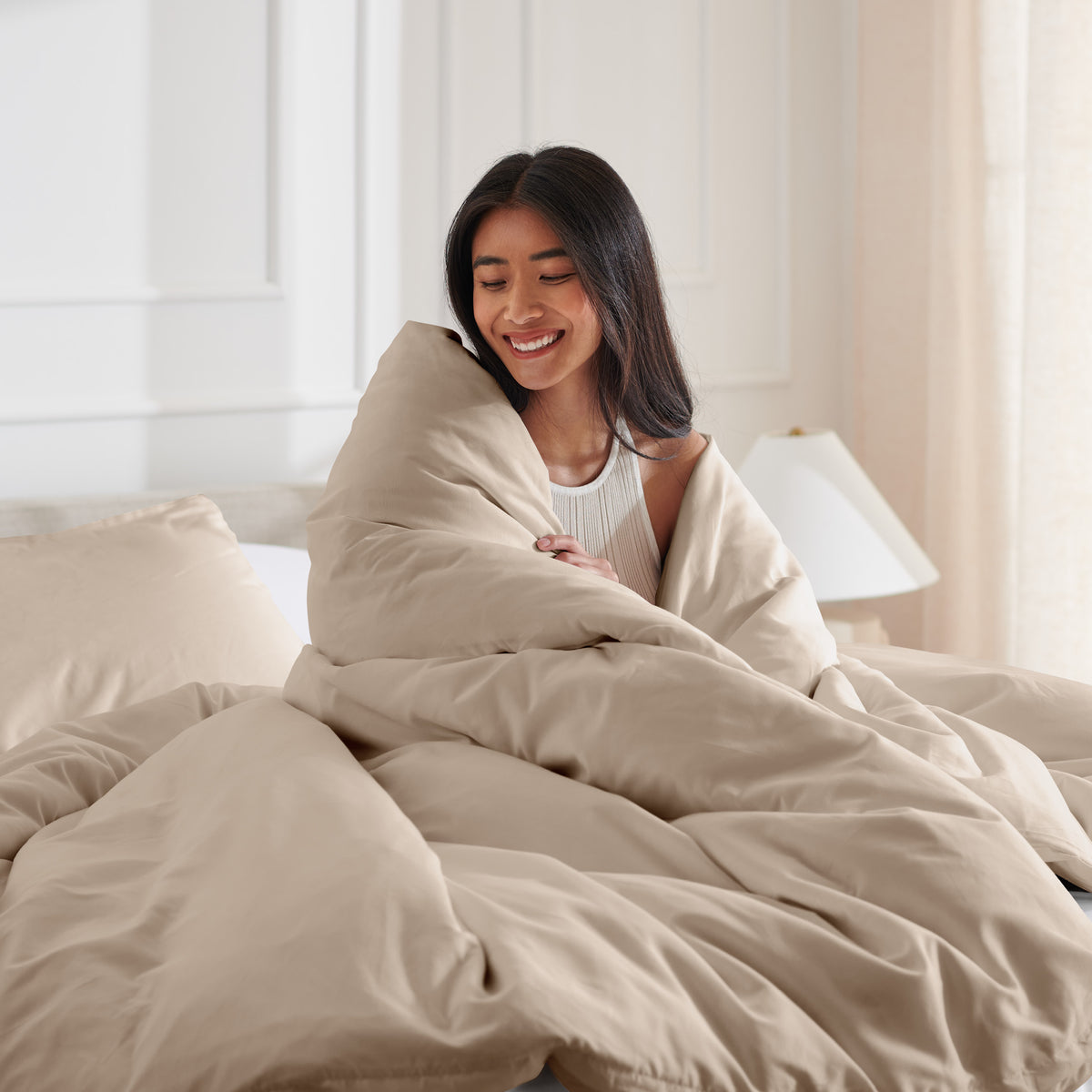 Woman smiling under duvet cover set in a bedroom setting