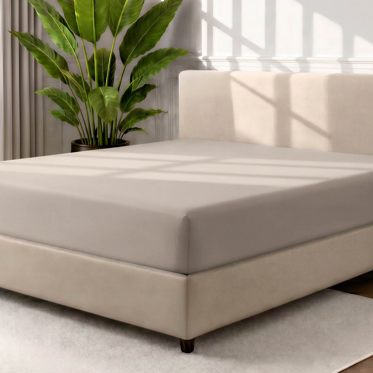 Man adjusting fitted sheet on a bed with white pillows.