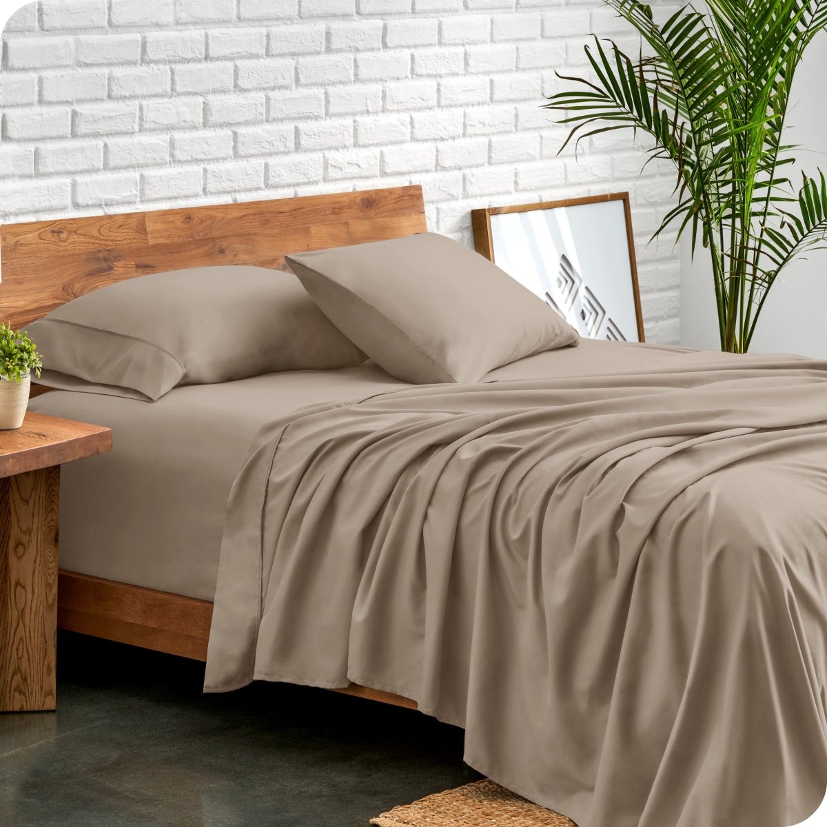 Bed with microfiber sheets against a white brick wall