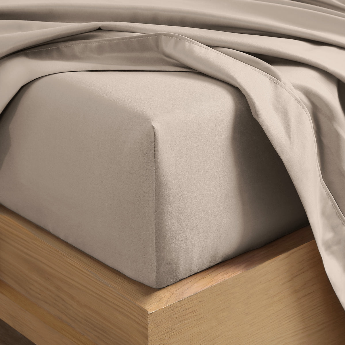 Close up of the corner of a mattress with a fitted sheet and flat sheet on it