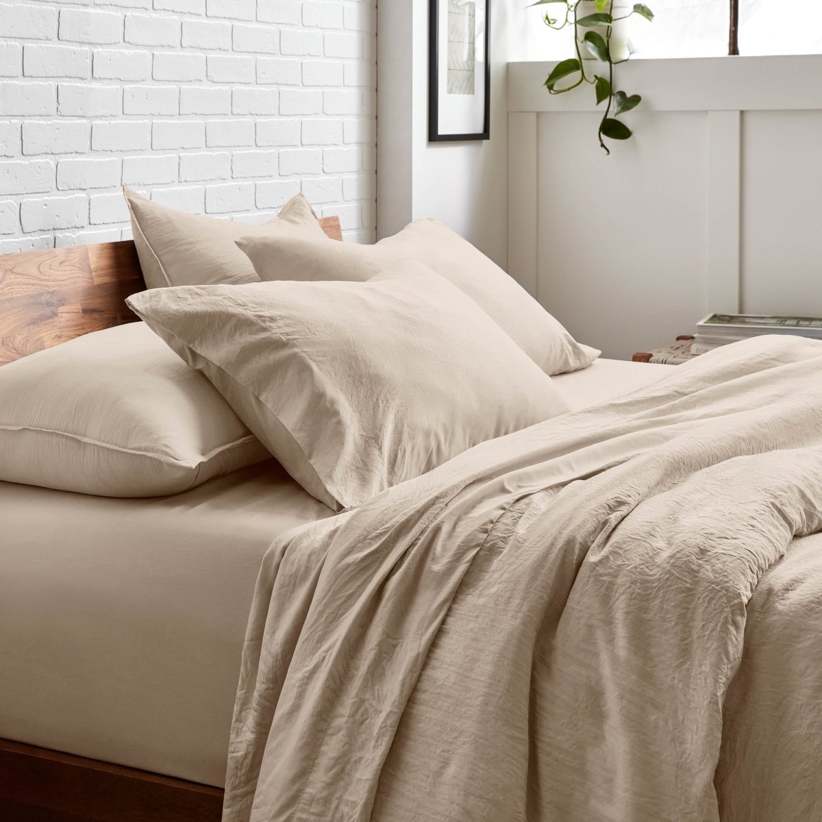 Bedding set on a bed with a white brick wall and window in the background