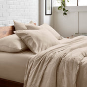 Bedding set on a bed with a white brick wall and window in the background