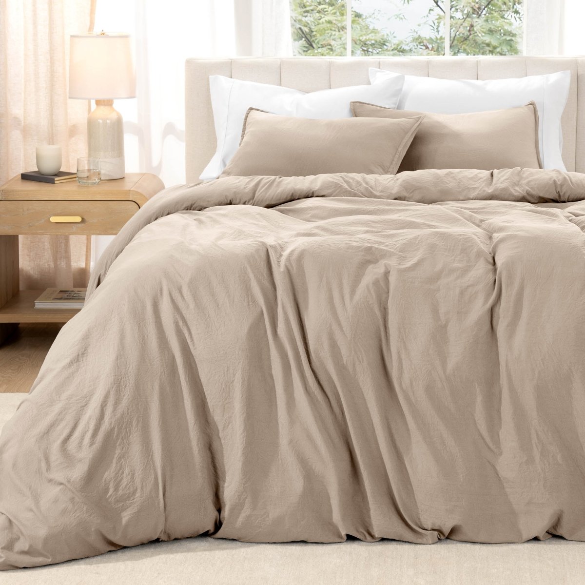Bed with washed bedding and white pillows in a bright room