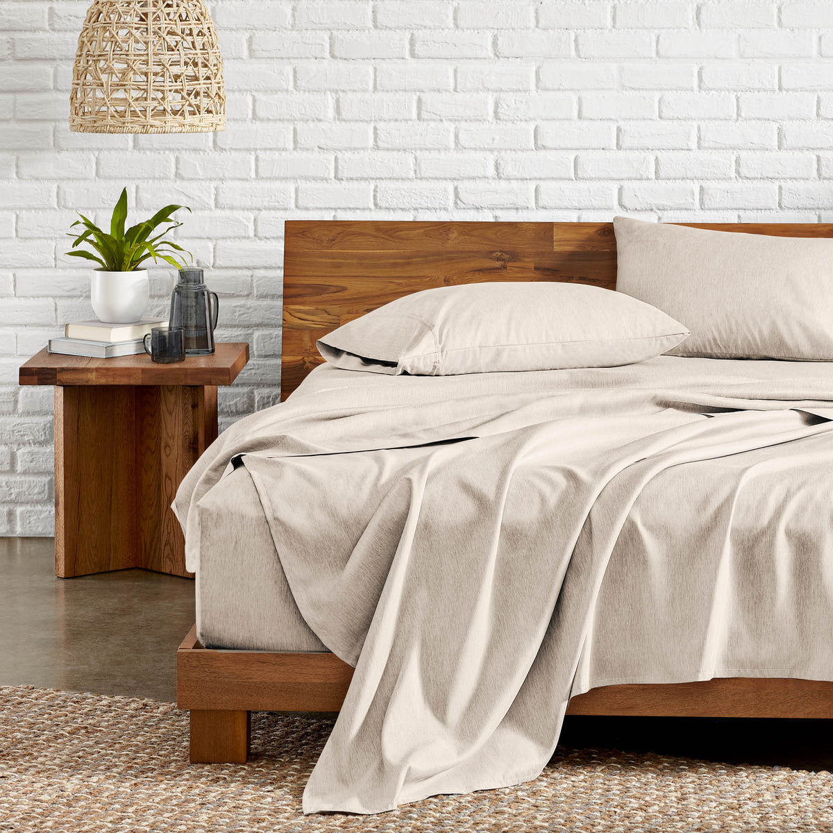 Bedroom with wooden bed, nightstand, and white brick wall.