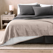 Bed with grey sheets and a sherpa blanket