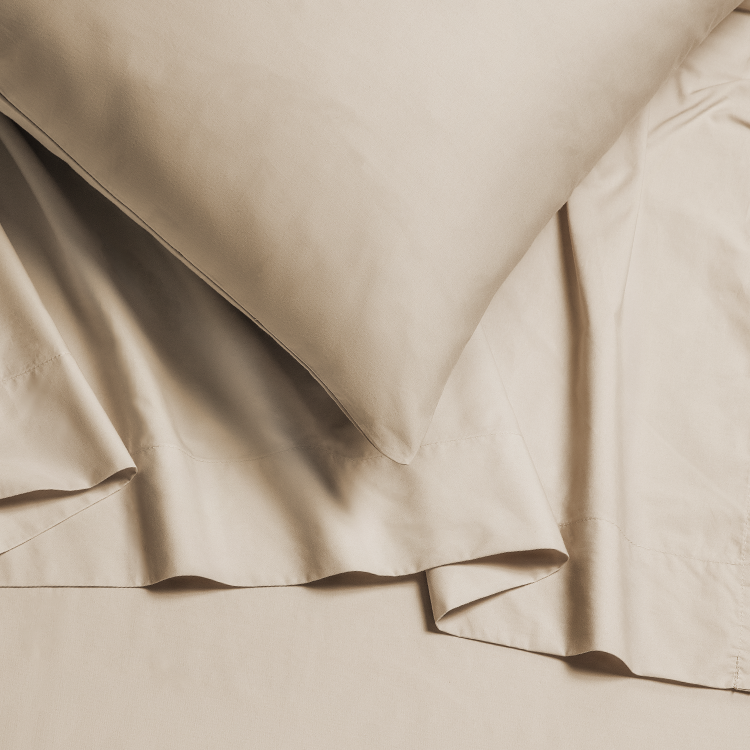 Beige bedding set with a pillow on a plain background
