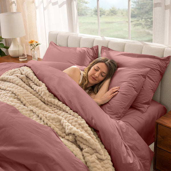 Woman sleeping in a bed with percale rosewood colored sheets and duvet