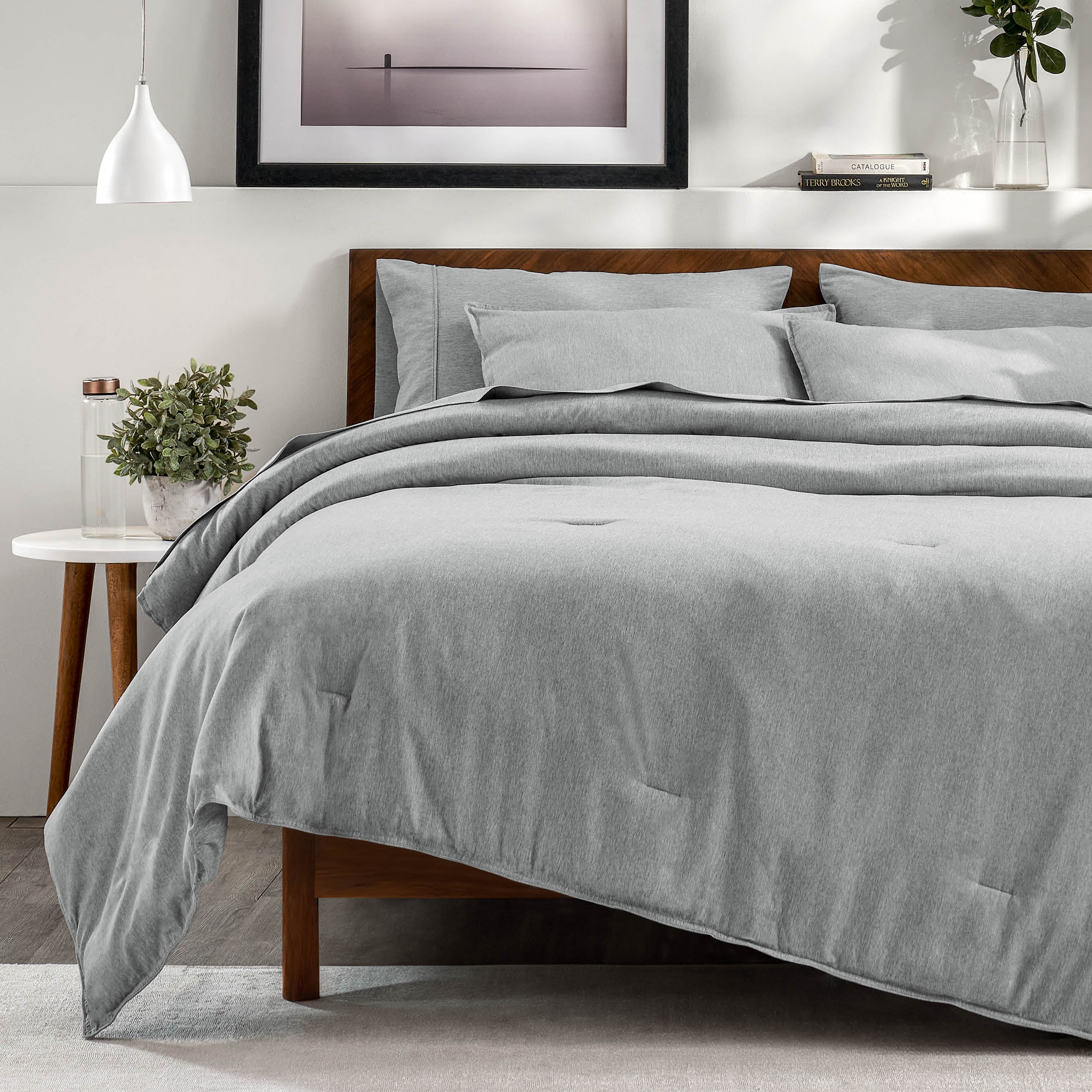 A bedroom with a side table, decor and a neatly made bed