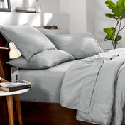 Bedding set on a bed in a bedroom with a side table and lamp.