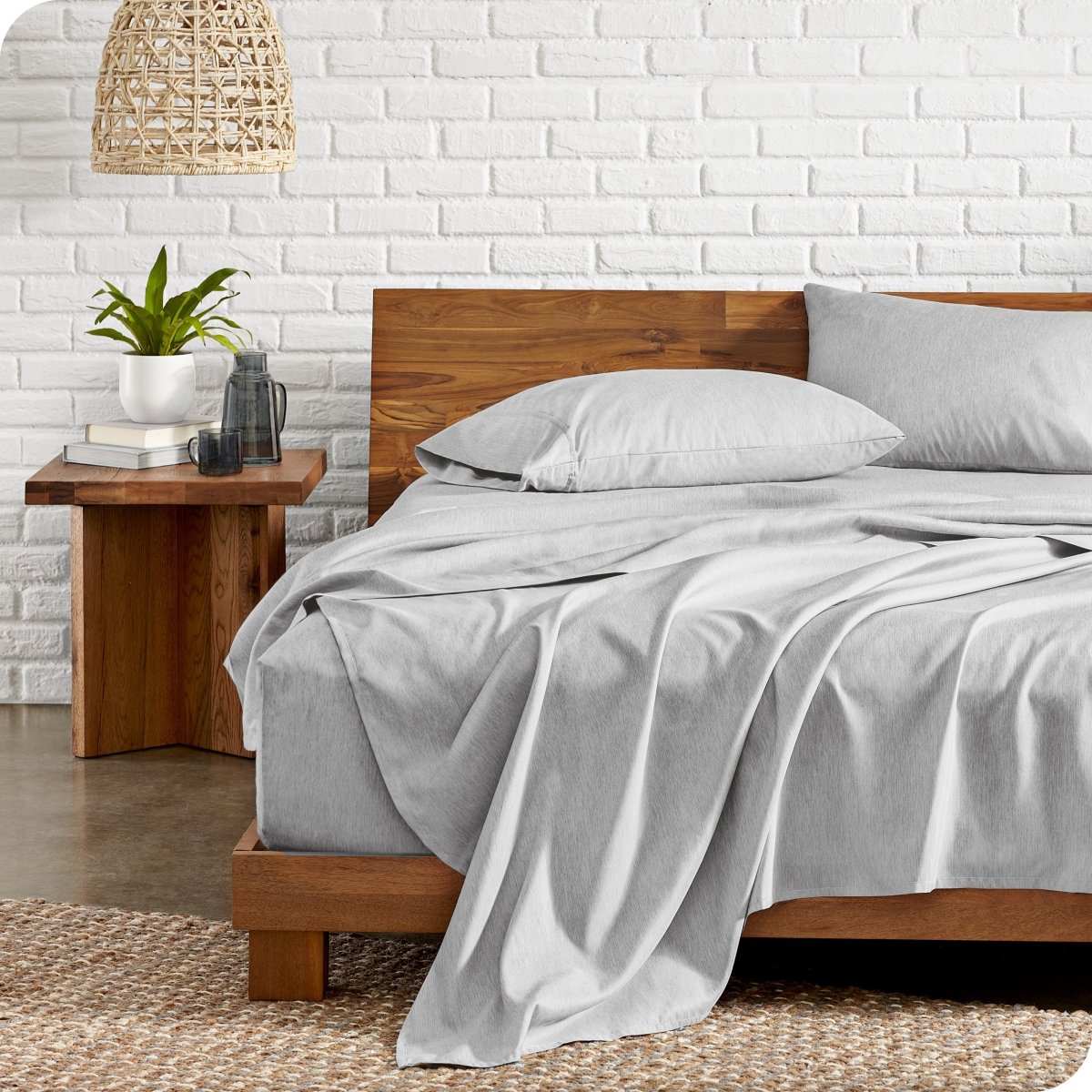 Bed with microfiber bedding against a white brick wall.