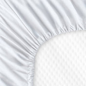 The back of a crib mattress with a fitted sheet on it