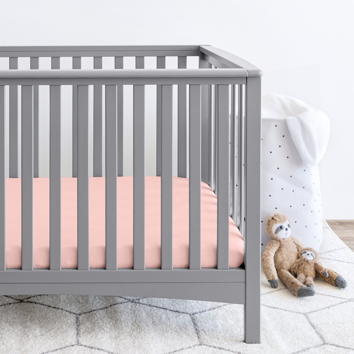Gray crib with stuffed animals on the floor next to it