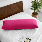 Pillowcase on a body pillow with a wooden headboard and plant in the background