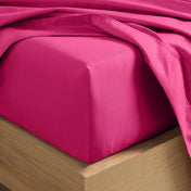 A close-up of a fitted sheet covering the corner of a bed frame, with matching top sheet draped over it.