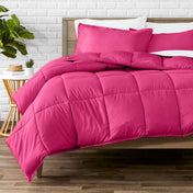 Comforter set on a bed with a white brick wall and plant in the background