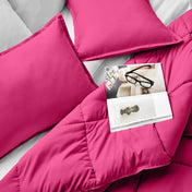 Comforter and pillows on a bed with a magazine and glasses.