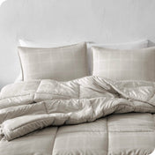 A comforter set on a bed against a white wall.