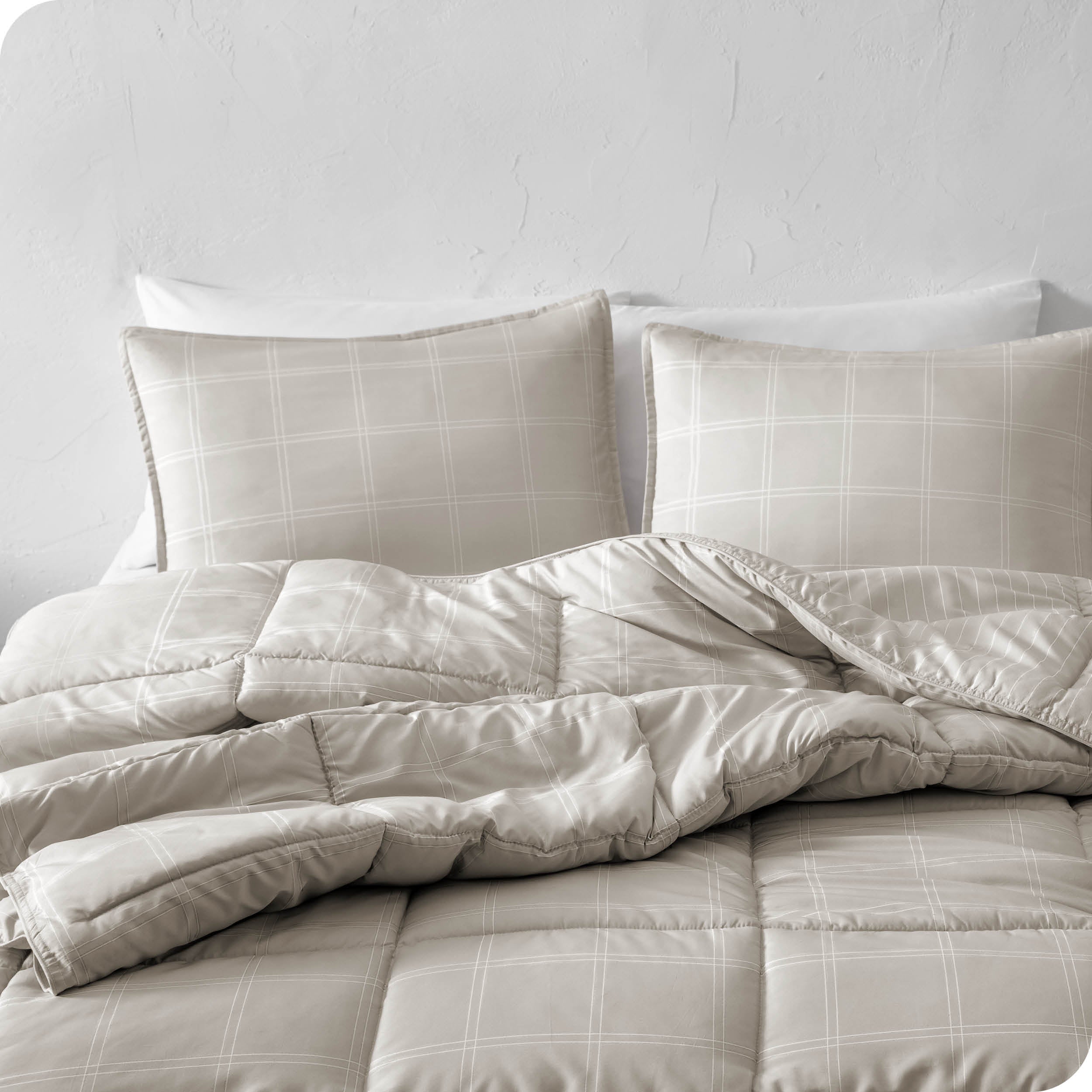 A comforter set on a bed against a white wall.
