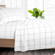 Side view of a bed made with white and grey plaid print sheets