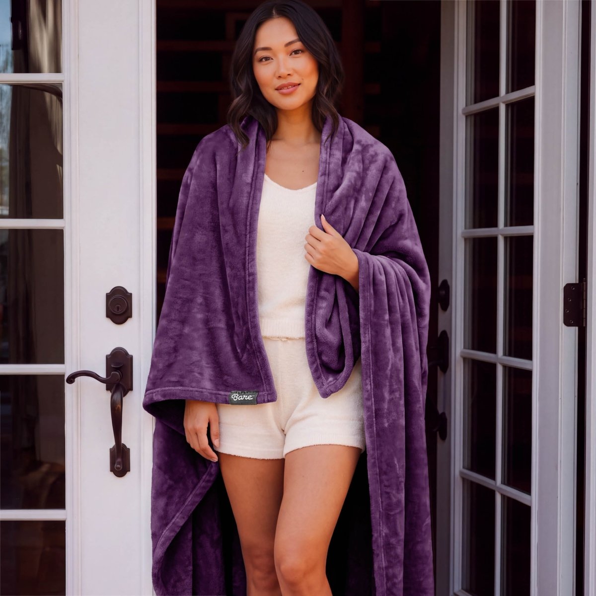 A woman standing with a microplush blanket wrapped around her