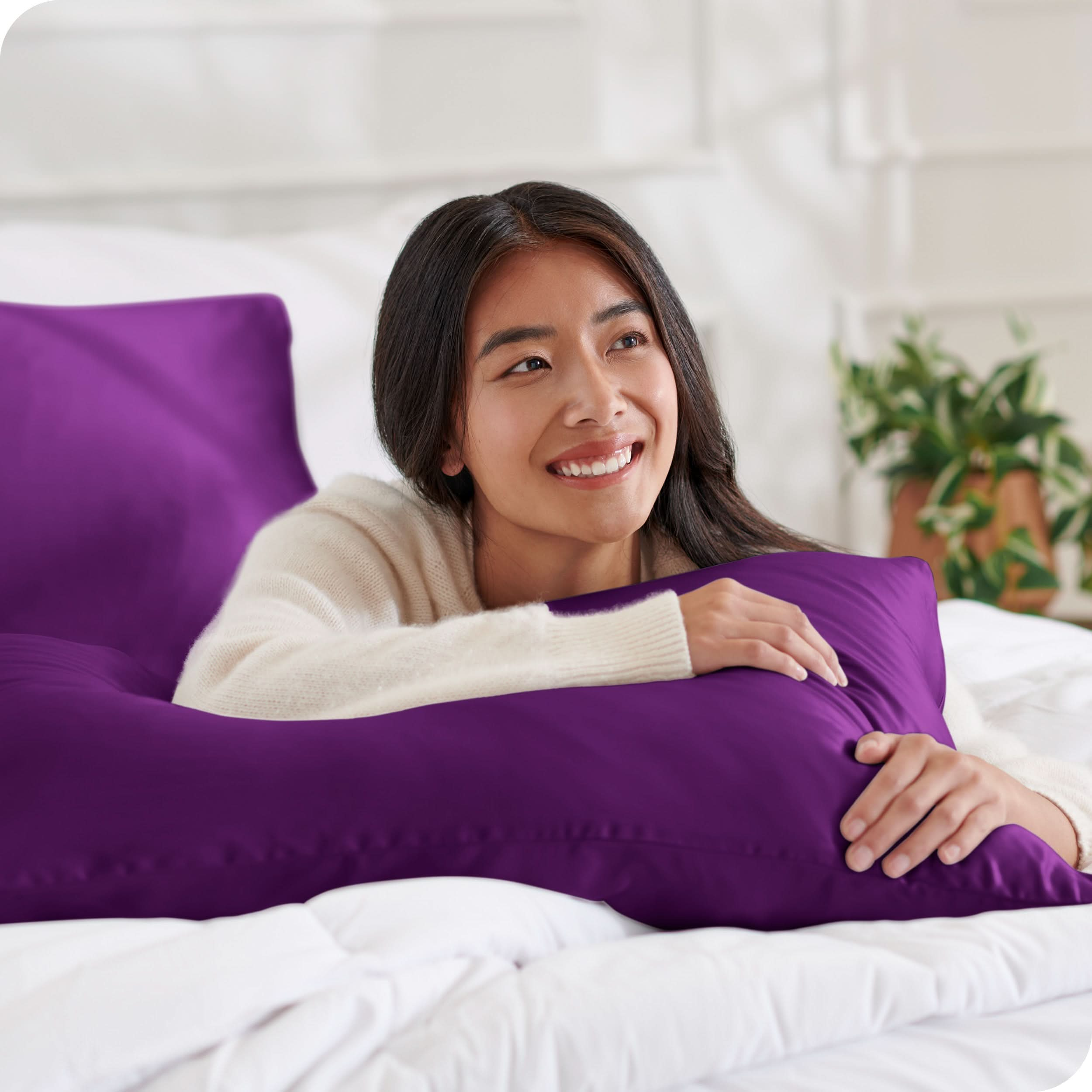 A woman on a bed with a silk pillowcase covered pillow