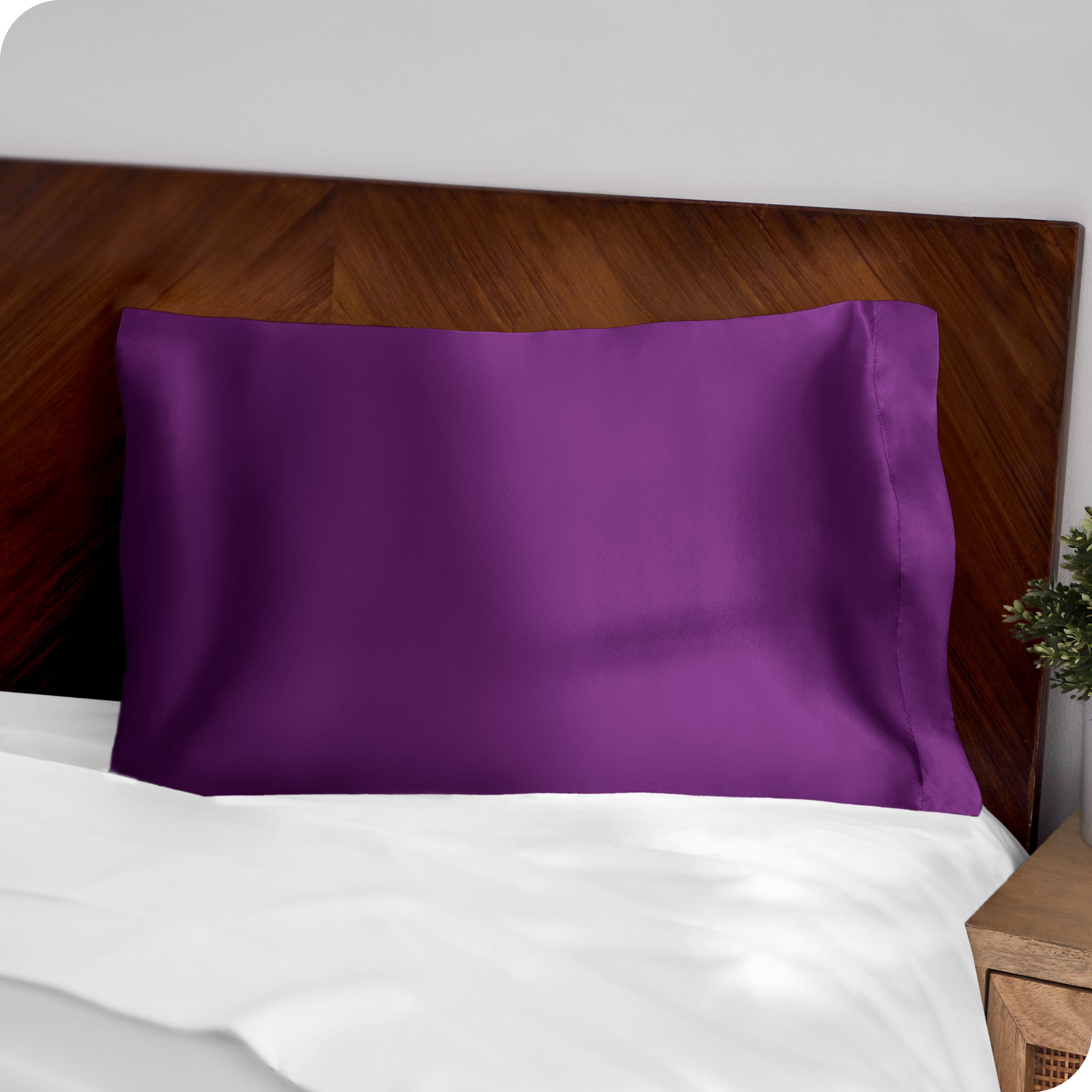 A purple silk pillowcase on a pillow resting on a headboard