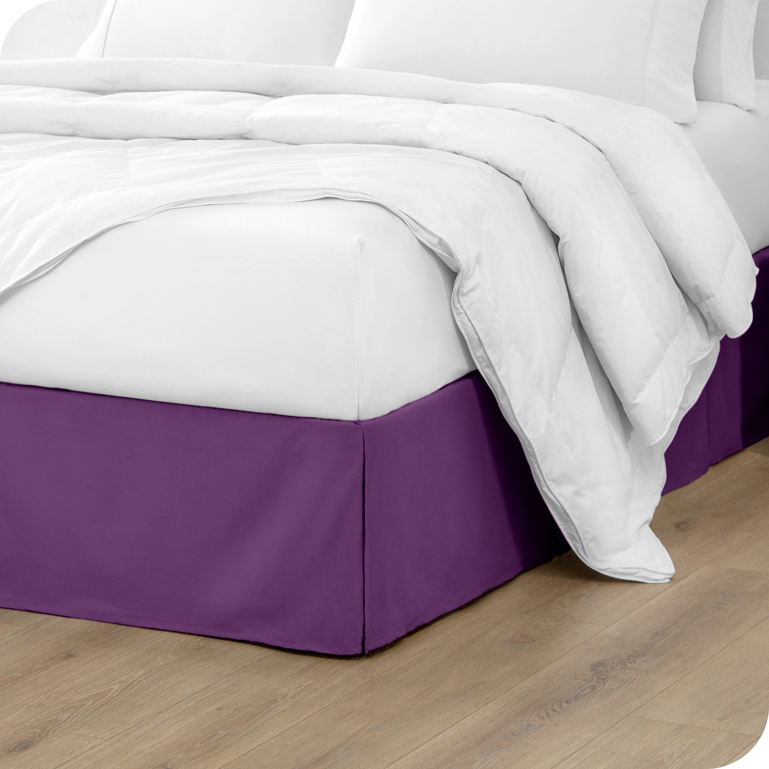 A modern bed with a microfiber bed skirt with pleats on the corners and midway on each side.