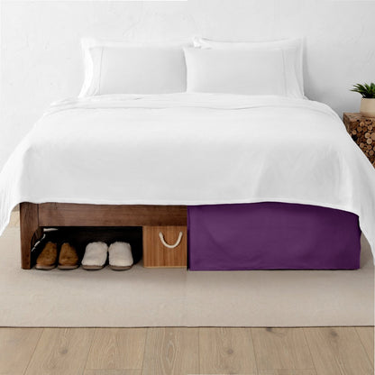 One side of a bed has shoes and a box under it while the other side has a bed skirt so that under the bed is hidden from view