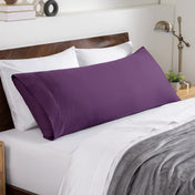 Bed sheets and pillows on a neatly made bed with a wooden headboard.