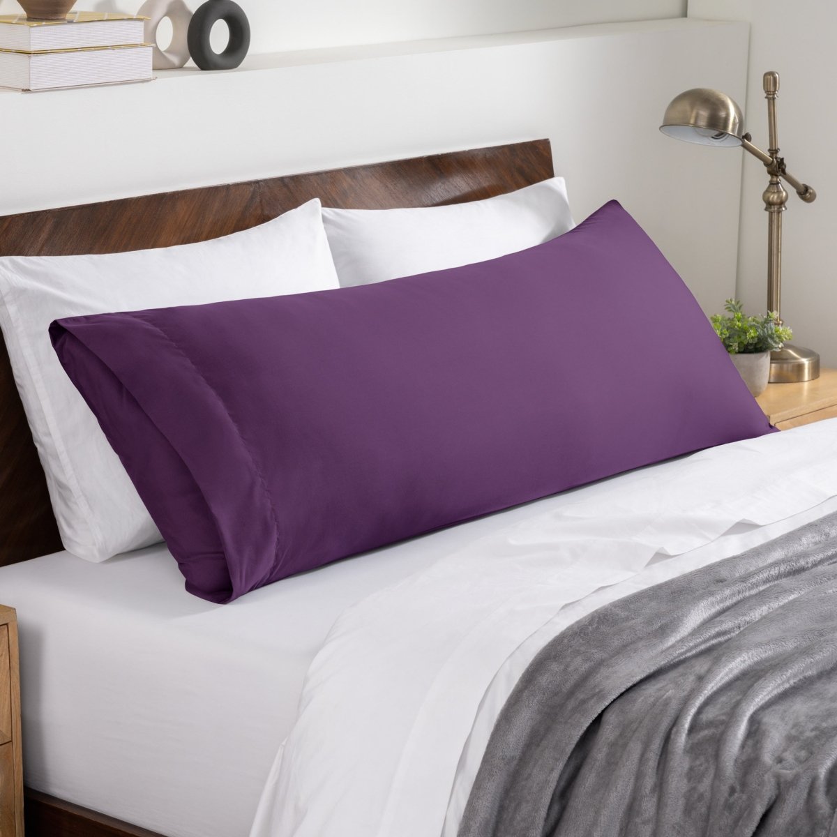 Bed sheets and pillows on a neatly made bed with a wooden headboard.