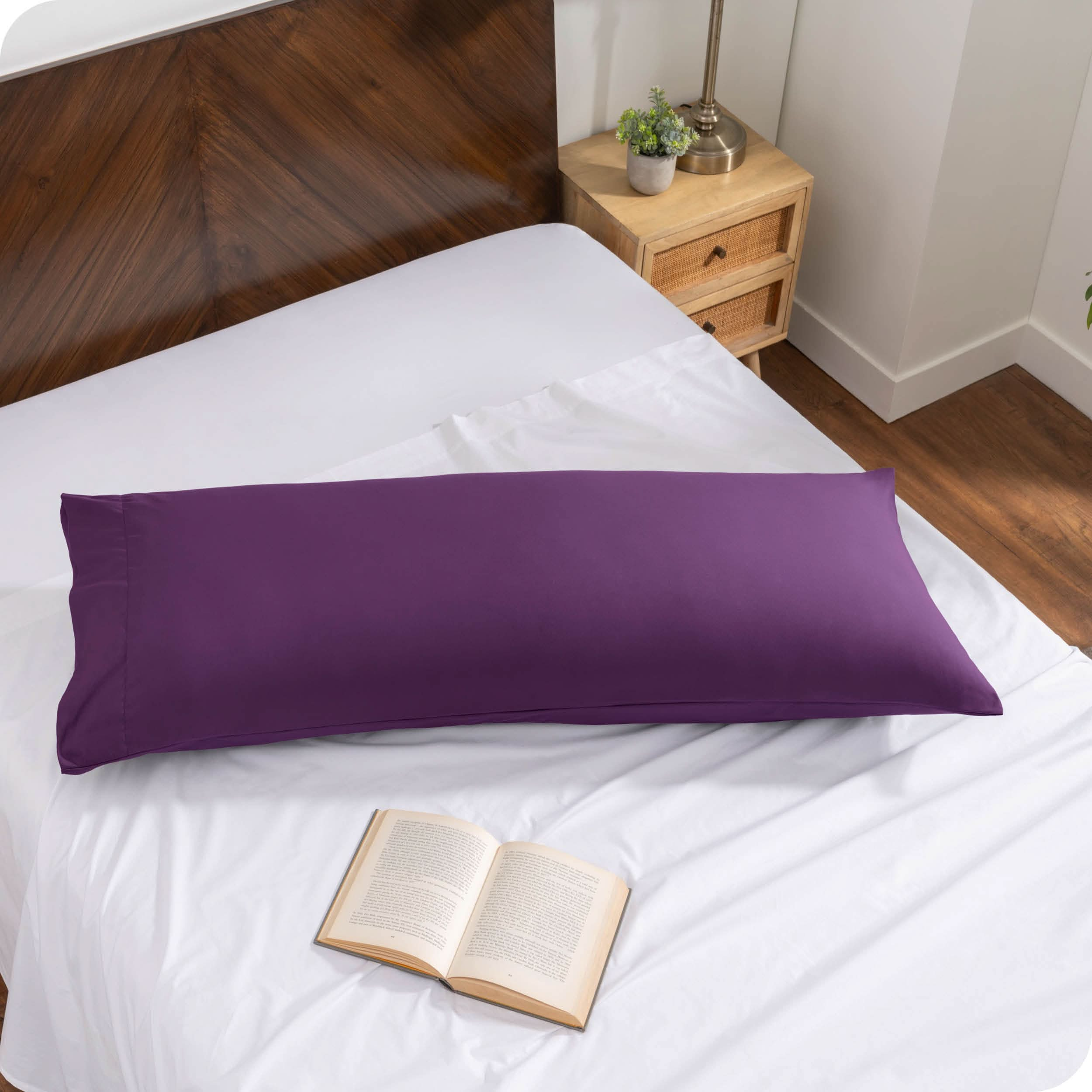 A body pillow cover on a pillow on a bed made with all white bedding