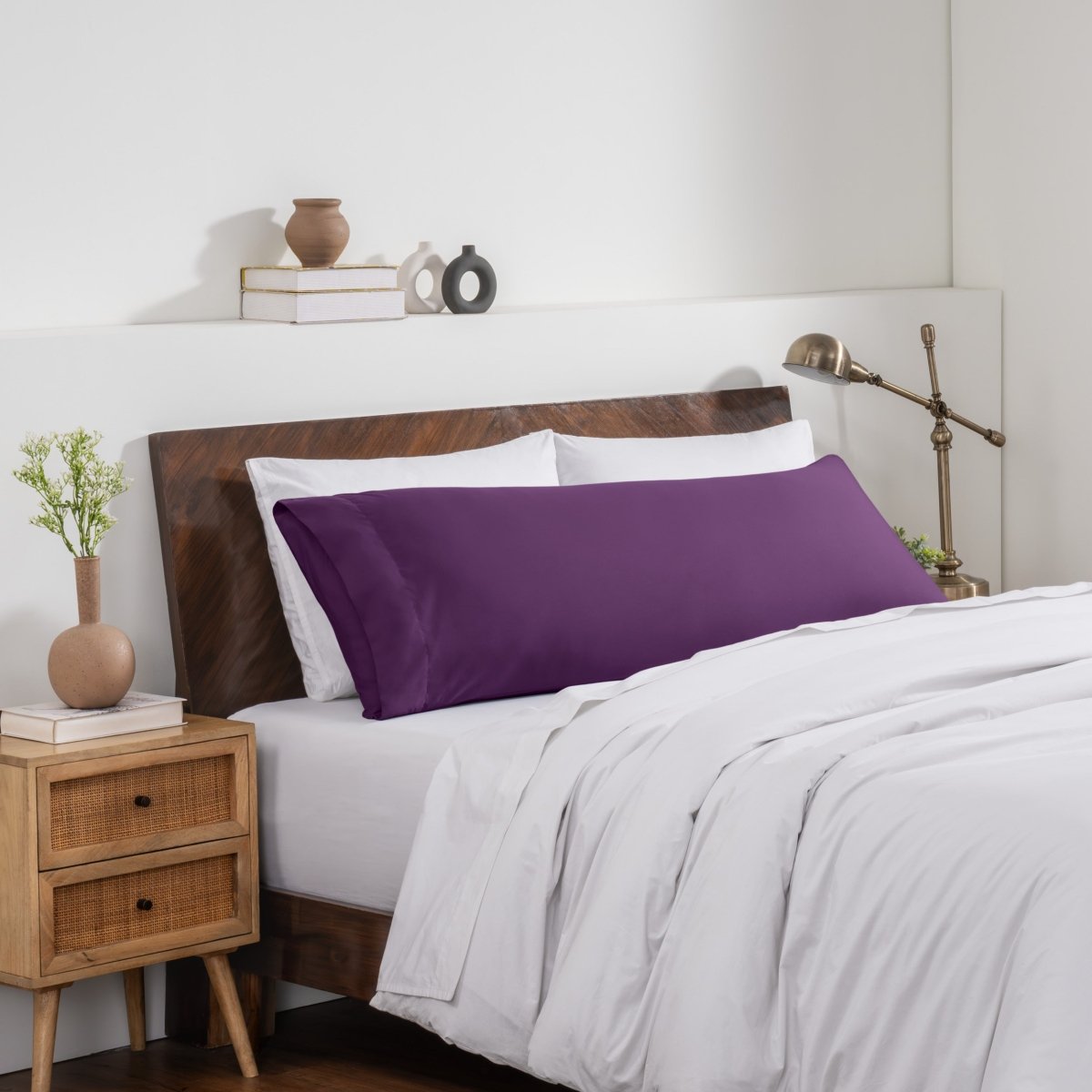 Bedroom with a wooden headboard and white bedding, featuring a nightstand and decorative items.