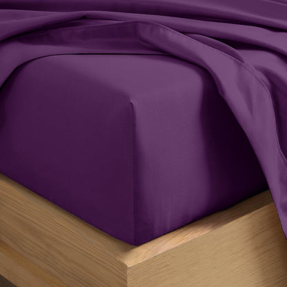 A close-up of a fitted sheet covering the corner of a bed frame, with matching top sheet draped over it.