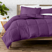 Comforter set on a bed with a white brick wall and plant in the background