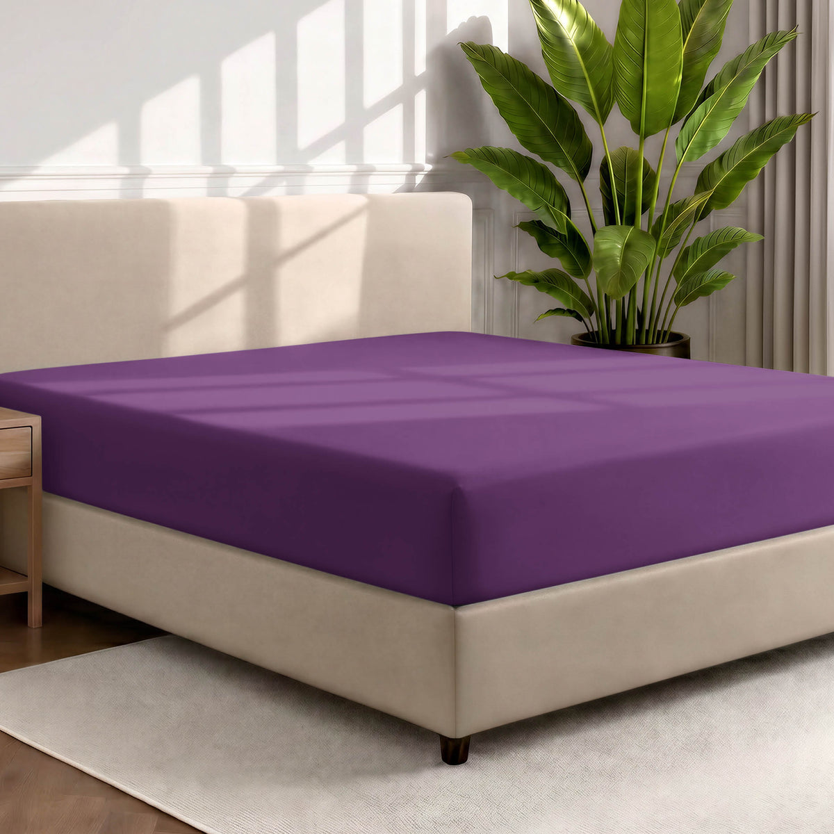 Bed with a fitted sheet in a room with a large plant and rug