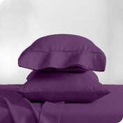 Two pillowcases on pillows stacked on a bed with matching sheets