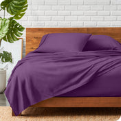 A wooden bed frame with a microfiber sheet set on the mattress.