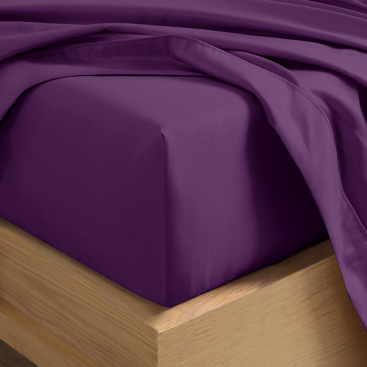 Close up of the corner of a mattress with a fitted sheet and flat sheet on it