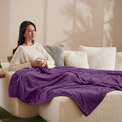 A woman sitting on a couch with a microplush blanket on her lap
