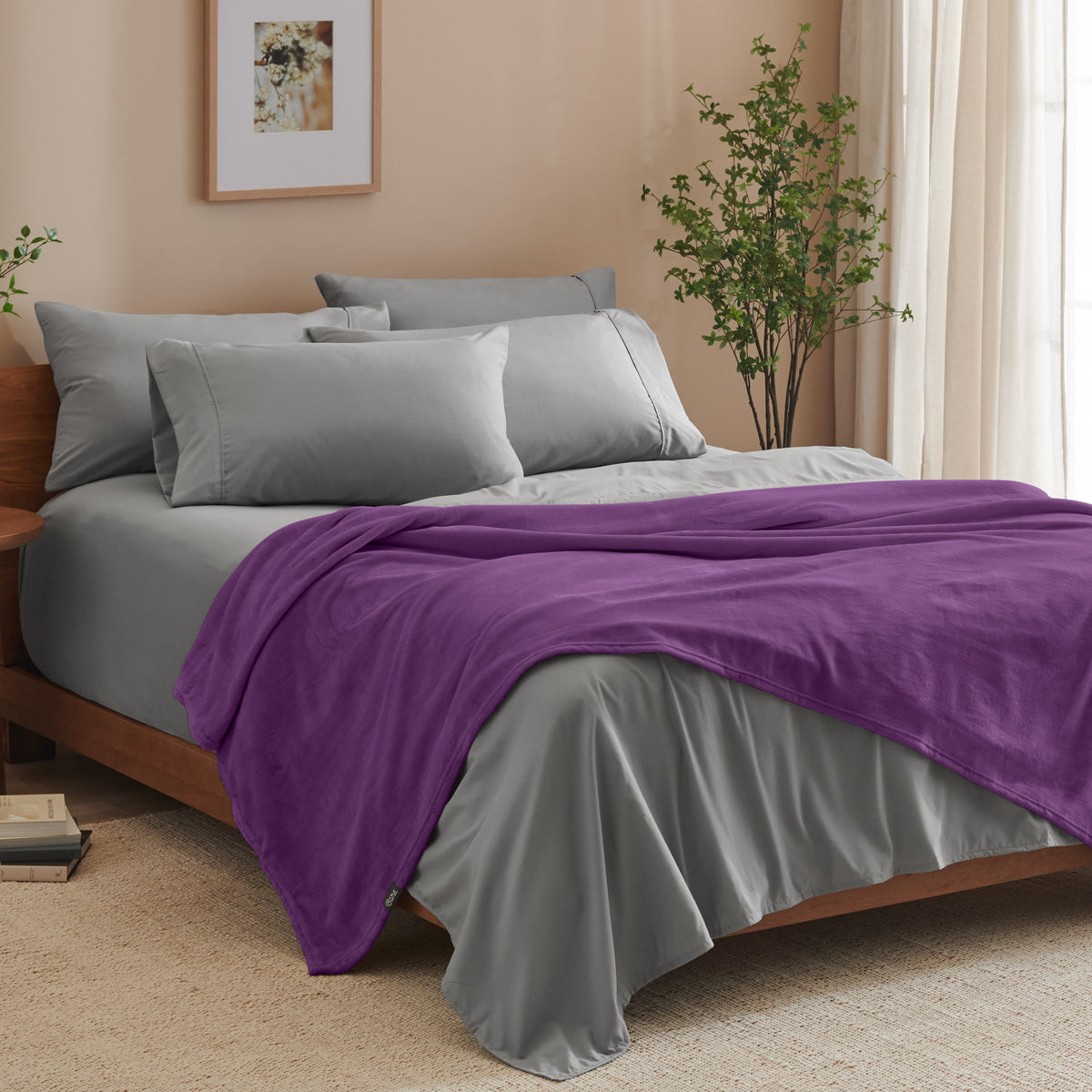 A bed made with grey sheets and a microplush blanket