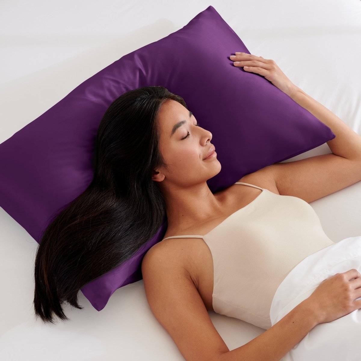 Woman lying on a bed with a pillow covered with a satin pillowcase