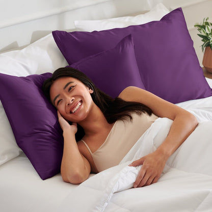 Woman lying on a bed with satin pillows and white bedding