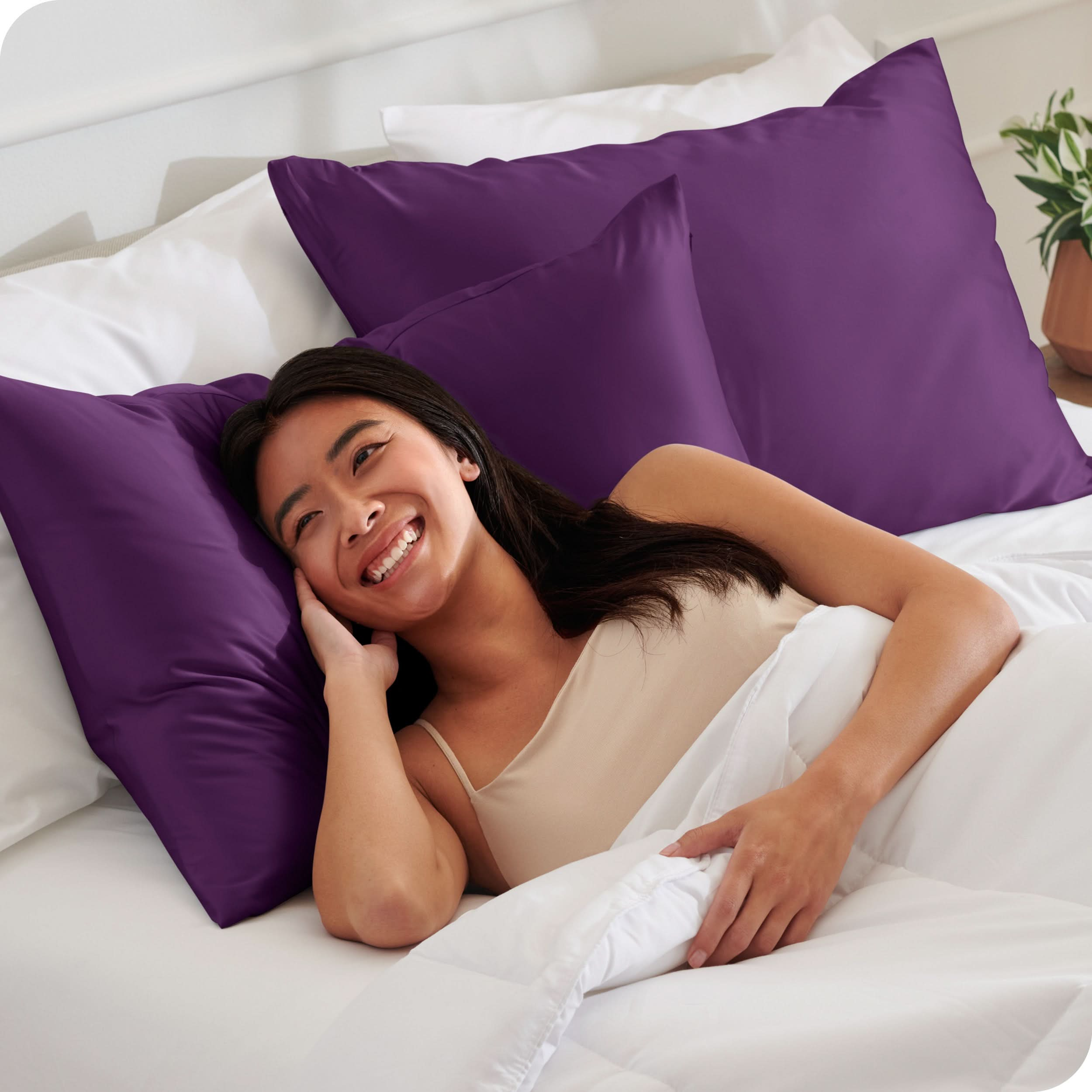 A woman is in bed and resting her head on a satin pillowcase