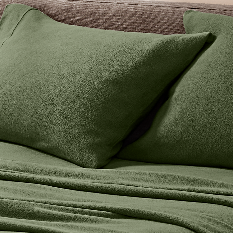 Green pillows and blanket on a textured surface