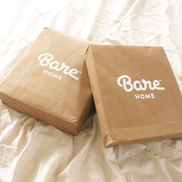 Two brown 'Bare Home' boxes on a white fabric background