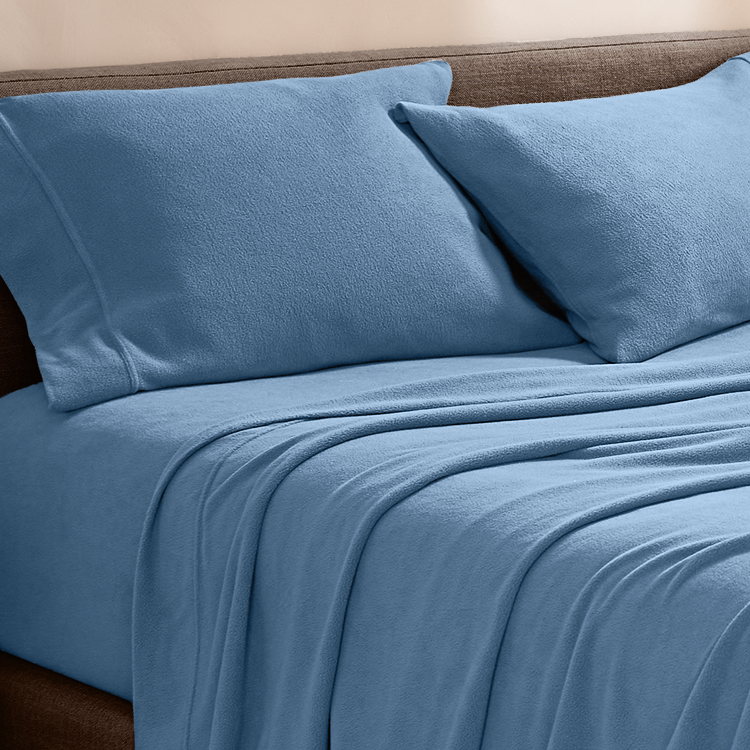 Blue bed sheets and pillows on a bed with a wooden headboard.