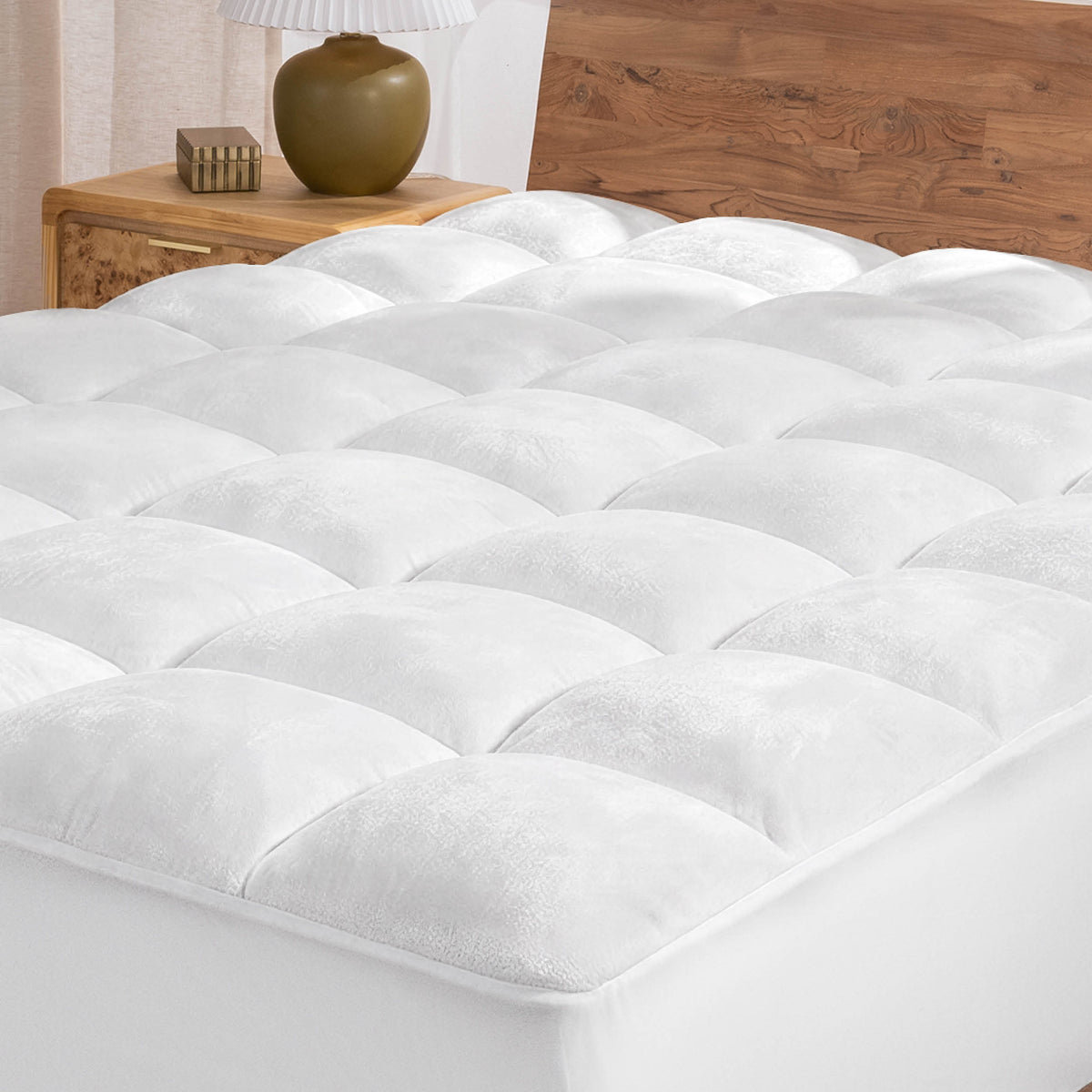 White mattress topper on a wooden bed with a neutral background