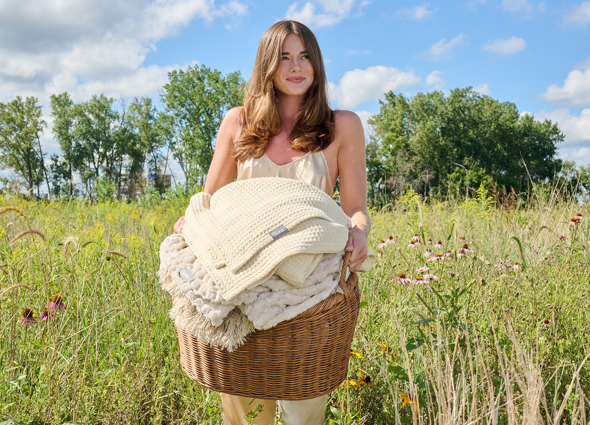 Pregnant woman standing outdoors in a grassy field holding a bundle