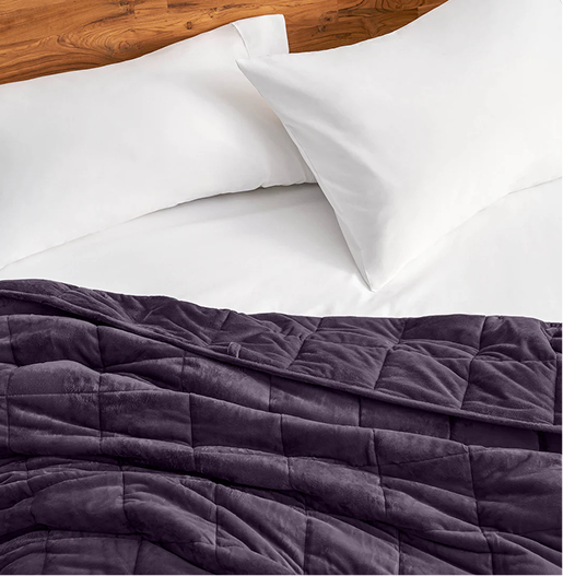 A purple weighted blanket on a bed