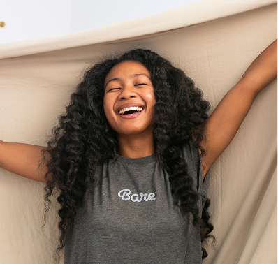 Smiling woman in a black tank top laughing with arms raised